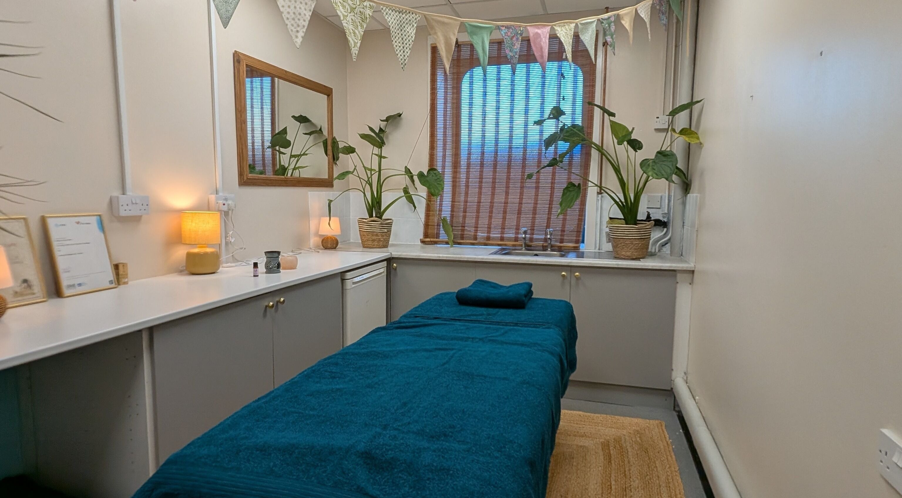 Relaxing treatment room at Wave Massage Studio, Portland, England, GB, with cozy decor and indoor plants.