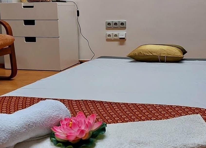 Tranquil massage setup at Lanta Thai Massage in Hlavní Město Praha, CZ featuring soft towels and lotus flower.