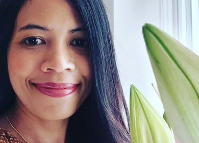 Staff at Lanta Thai Massage, Hlavní Město Praha, offers a welcoming smile with floral decor enhancing the serene setting.