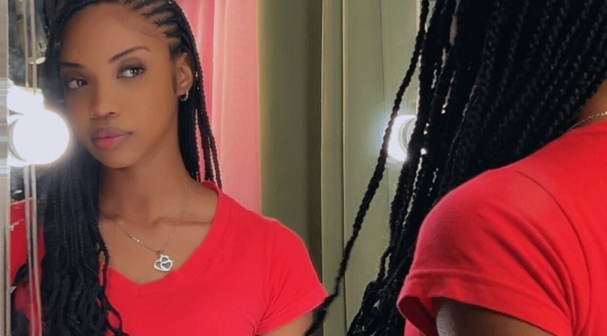 Woman with braided hair at JusstBraids, Oistins, Christ Church, BB, looking into a mirror.