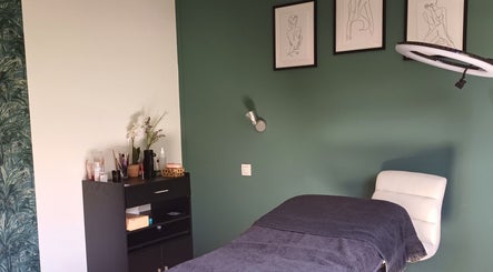 Sala de tratamiento en Curvas, Villemoustaussou, Occitanie, FR, con decoración moderna y una camilla.
