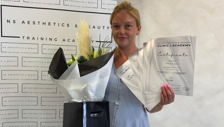 Graduated beauty professional at Angel Face, Shildon, England, GB, holding certificates and flowers.
