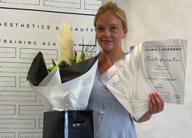 Graduated beauty professional at Angel Face, Shildon, England, GB, holding certificates and flowers.