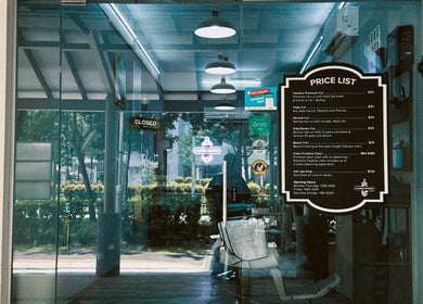 Entrance of Hombre Barbers (Tampines) with price list displayed, located in Singapore, Singapore, SG.
