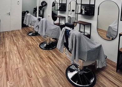Interior of Hombre Barbers (Bishan) in Singapore showcasing stylish barber chairs and modern decor.