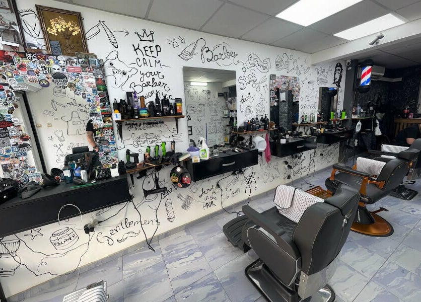 Интериор на Evolution Barber Shop, Пловдив, с артистично изрисувани стени и оборудване за подстригване.
