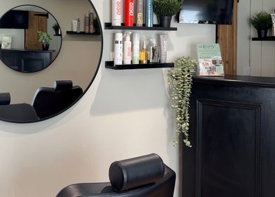 Modern salon interior at tweakhair, Fakenham, England, GB featuring stylish mirror and product shelves.
