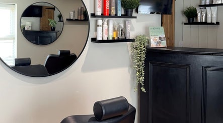 Modern salon interior at tweakhair, Fakenham, England, GB featuring stylish mirror and product shelves.