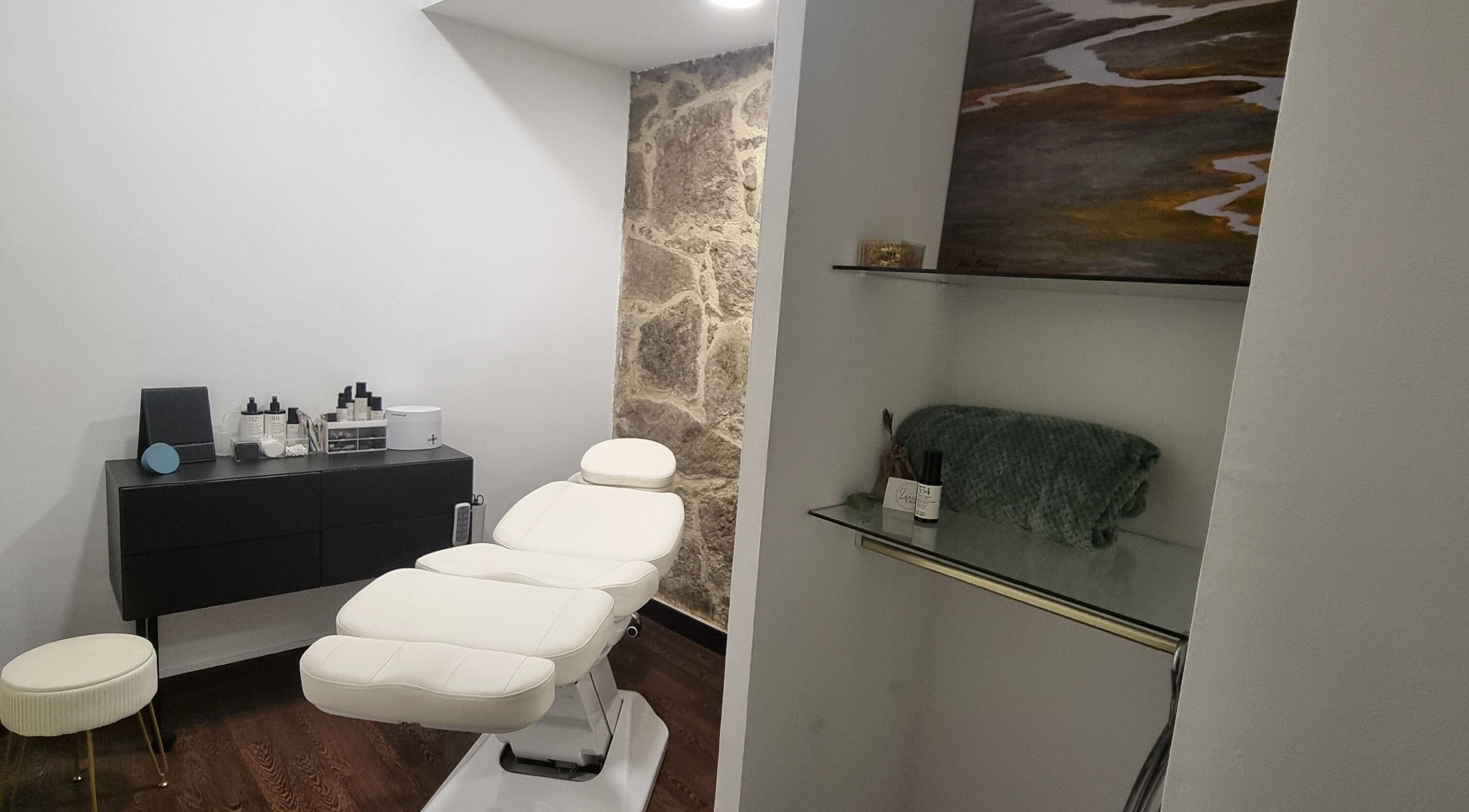 Interior de salón en Lucia Lago Vigo, ES, con camilla blanca y decoración moderna.