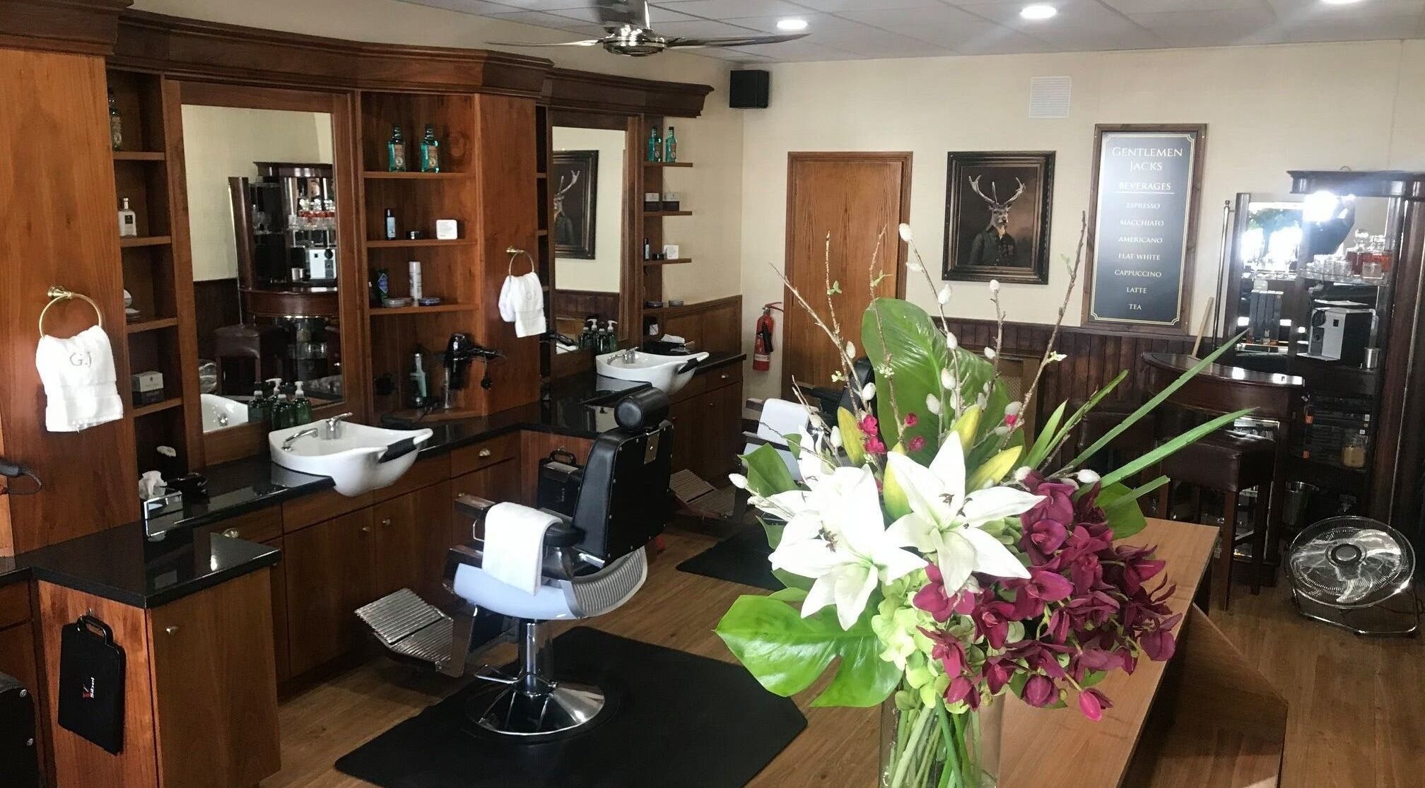 Interior of Gentlemen Jack's barbershop, Eastbourne, England, featuring wooden furnishings and floral decor.