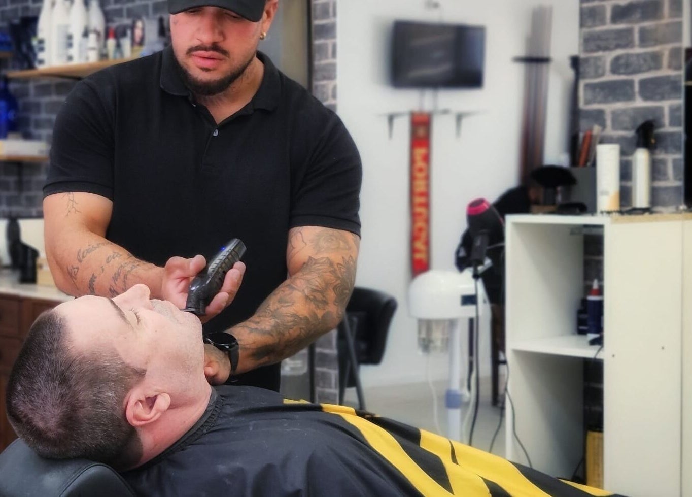 Profissional ajusta barba em cliente na Reis Barbearia, Leiria, Leiria, PT, com ambiente moderno e acolhedor.