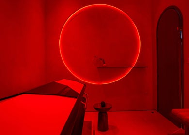 AKARI wellness room in District, دبي, AE, featuring a red-hued infrared therapy space with a glowing circle.