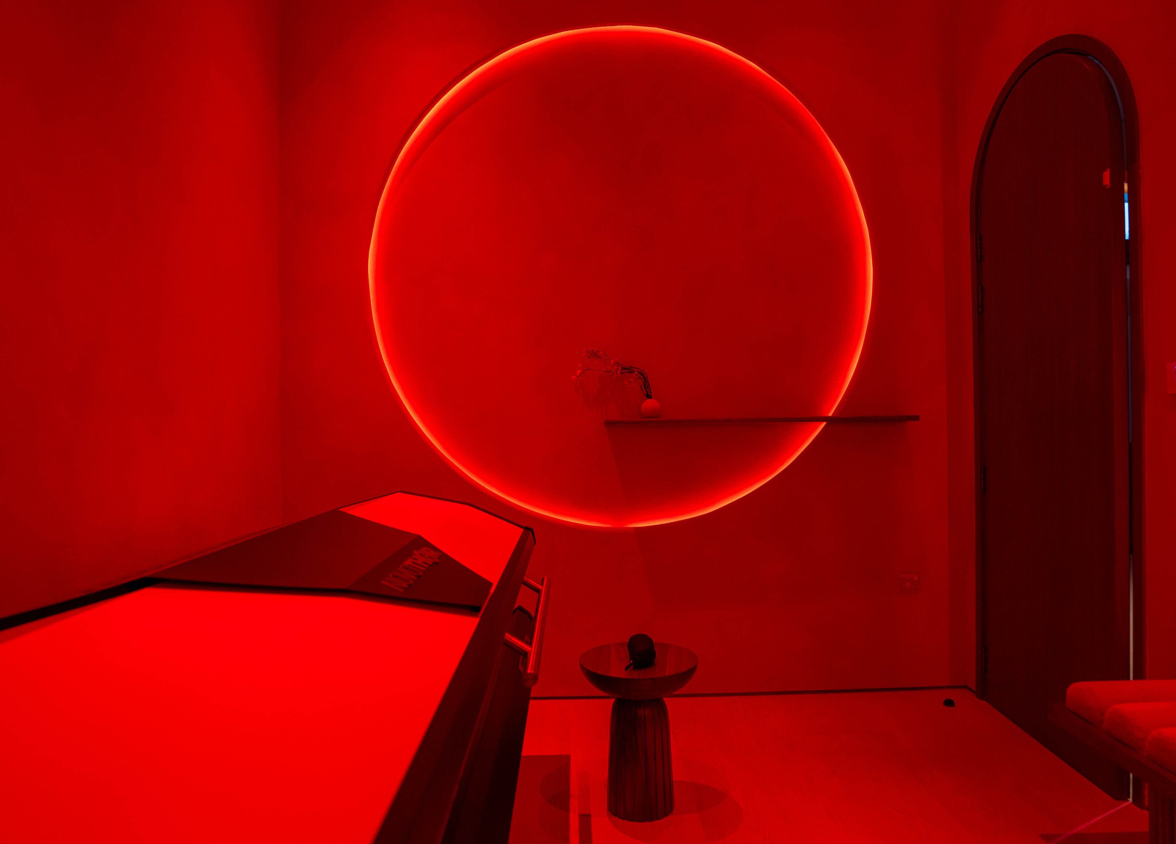 AKARI wellness room in District, دبي, AE, featuring a red-hued infrared therapy space with a glowing circle.