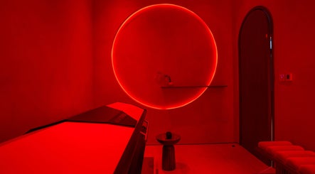 AKARI wellness room in District, دبي, AE, featuring a red-hued infrared therapy space with a glowing circle.