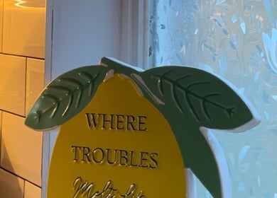 Decorative lemon sign at Sabrina’s, Brighton, England, GB, invites relaxation with 'Where troubles melt like'.