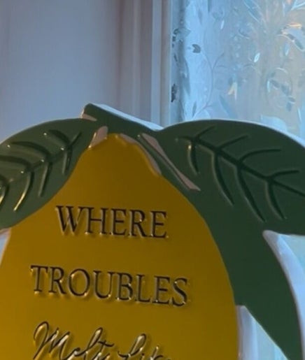 Decorative lemon sign at Sabrina’s, Brighton, England, GB, invites relaxation with 'Where troubles melt like'.