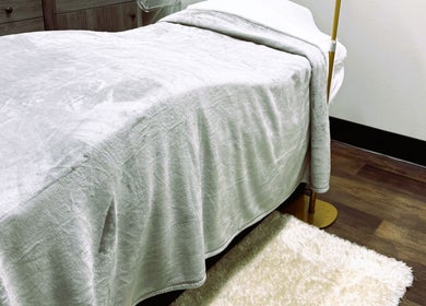 Cozy treatment bed at Serenity Aesthetics & Spa, Charlotte, North Carolina, US, with a soft gray blanket.