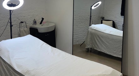 Calming treatment room at TINTD Society, Paynes Hall, England, GB featuring massage bed and soft lighting.