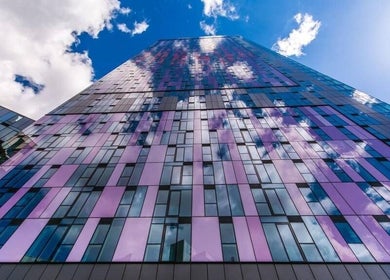 Modern glass skyscraper exterior at JZ Nailed It, Croydon, England, GB reflecting blue sky and clouds.