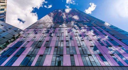 Modern glass skyscraper exterior at JZ Nailed It, Croydon, England, GB reflecting blue sky and clouds.