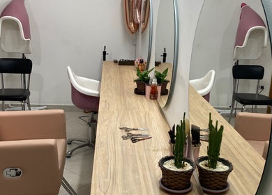 Mesa elegante no Studiocrespa&cacheada em São Paulo, SP, BR, com espelho grande, plantas e poltronas de beleza.