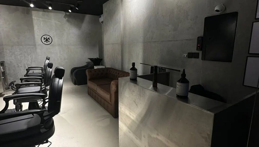 Chic interior of MERAK BARBERSHOP in Jeddah, Makkah Province, SA with black chairs and a brown sofa.