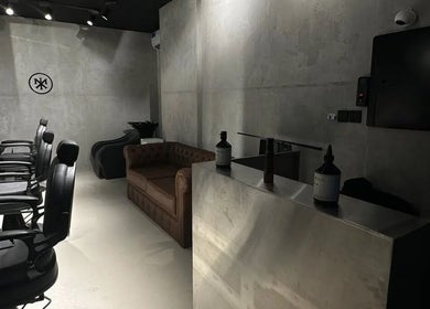 Chic interior of MERAK BARBERSHOP in Jeddah, Makkah Province, SA with black chairs and a brown sofa.