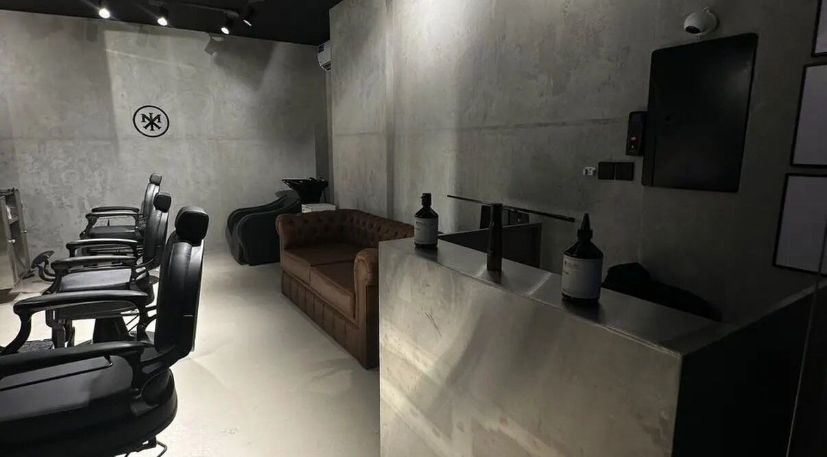 Chic interior of MERAK BARBERSHOP in Jeddah, Makkah Province, SA with black chairs and a brown sofa.
