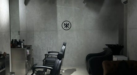Interior of MERAK BARBERSHOP in Jeddah, featuring modern chairs against sleek gray walls.