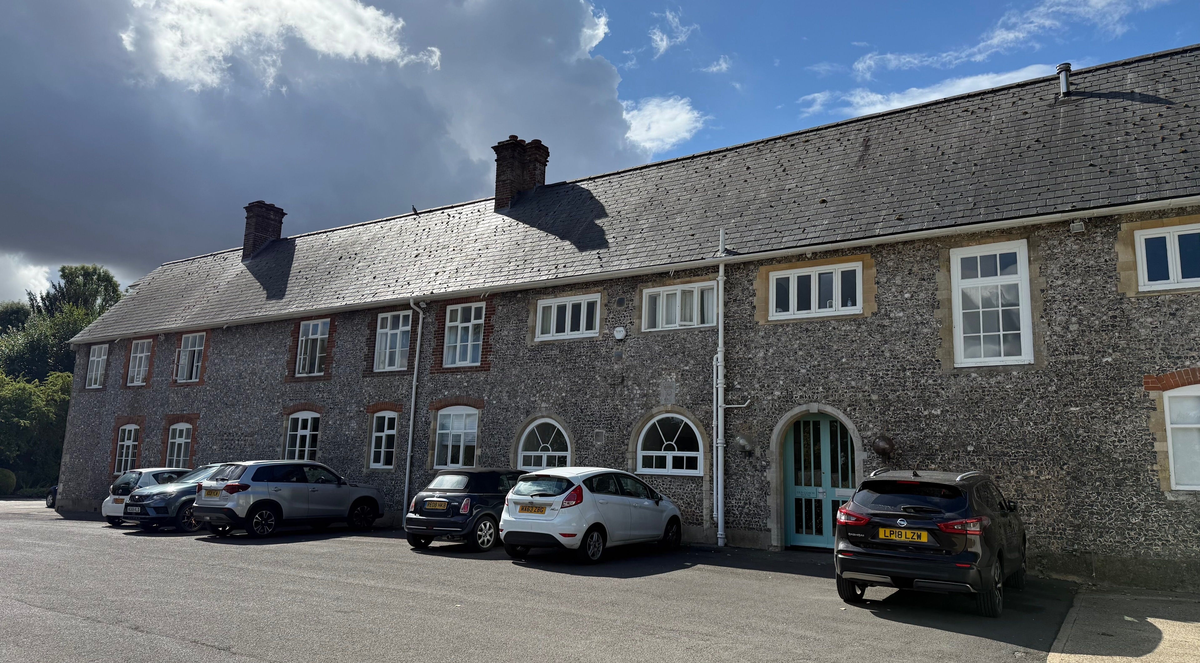 Front view of Chloë Jane Aesthetics' historic building in Farleigh Wallop, England, GB, under a cloudy sky.
