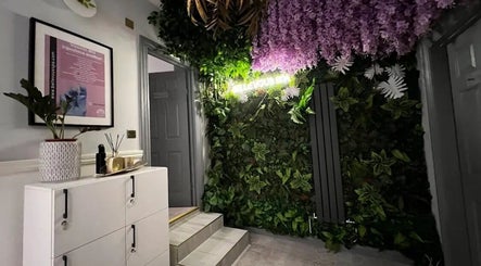 Green wall with purple flowers at PureLi Skin Clinic, London, England, GB, creating a serene entrance.