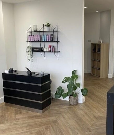 Spacious, modern interior of Libby’s Hair, Worthing, England, GB, featuring sleek black furniture and plant decor.