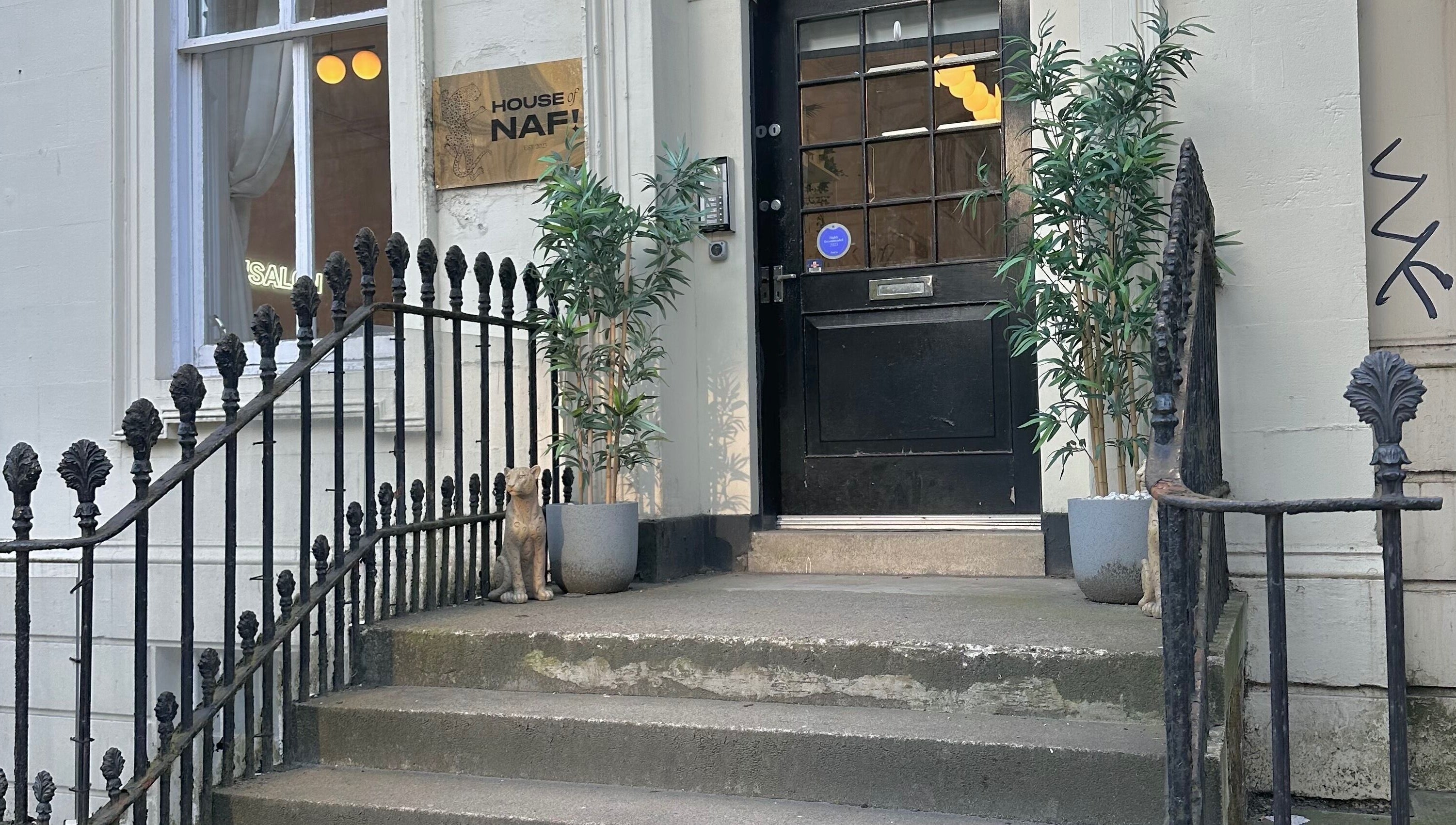 Elegant entrance at LMS Nails in Glasgow, Scotland, GB, with potted plants and a decorative cat.