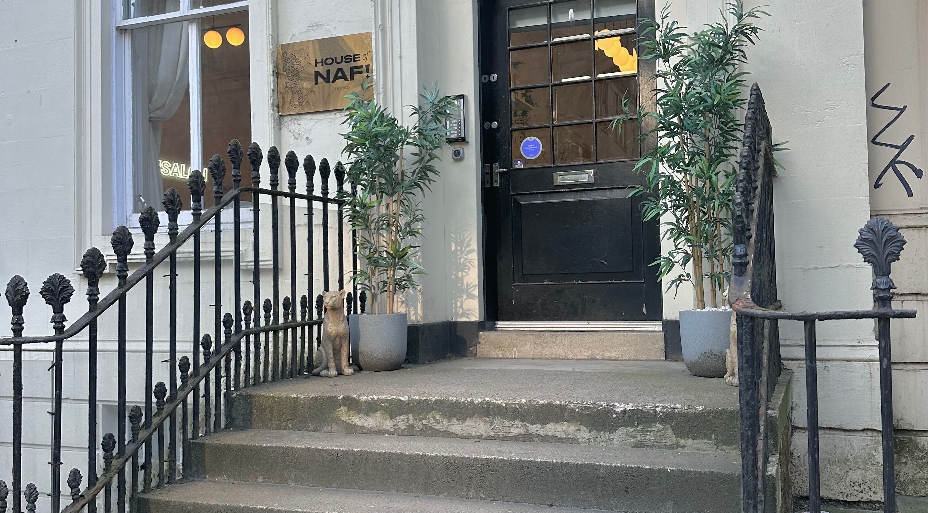 Elegant entrance at LMS Nails in Glasgow, Scotland, GB, with potted plants and a decorative cat.