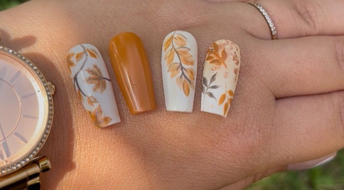 Nail art automnal à Sublima’Elle, Moret-loing-et-orvanne, FR. Design élégant de feuilles et tons ocres.