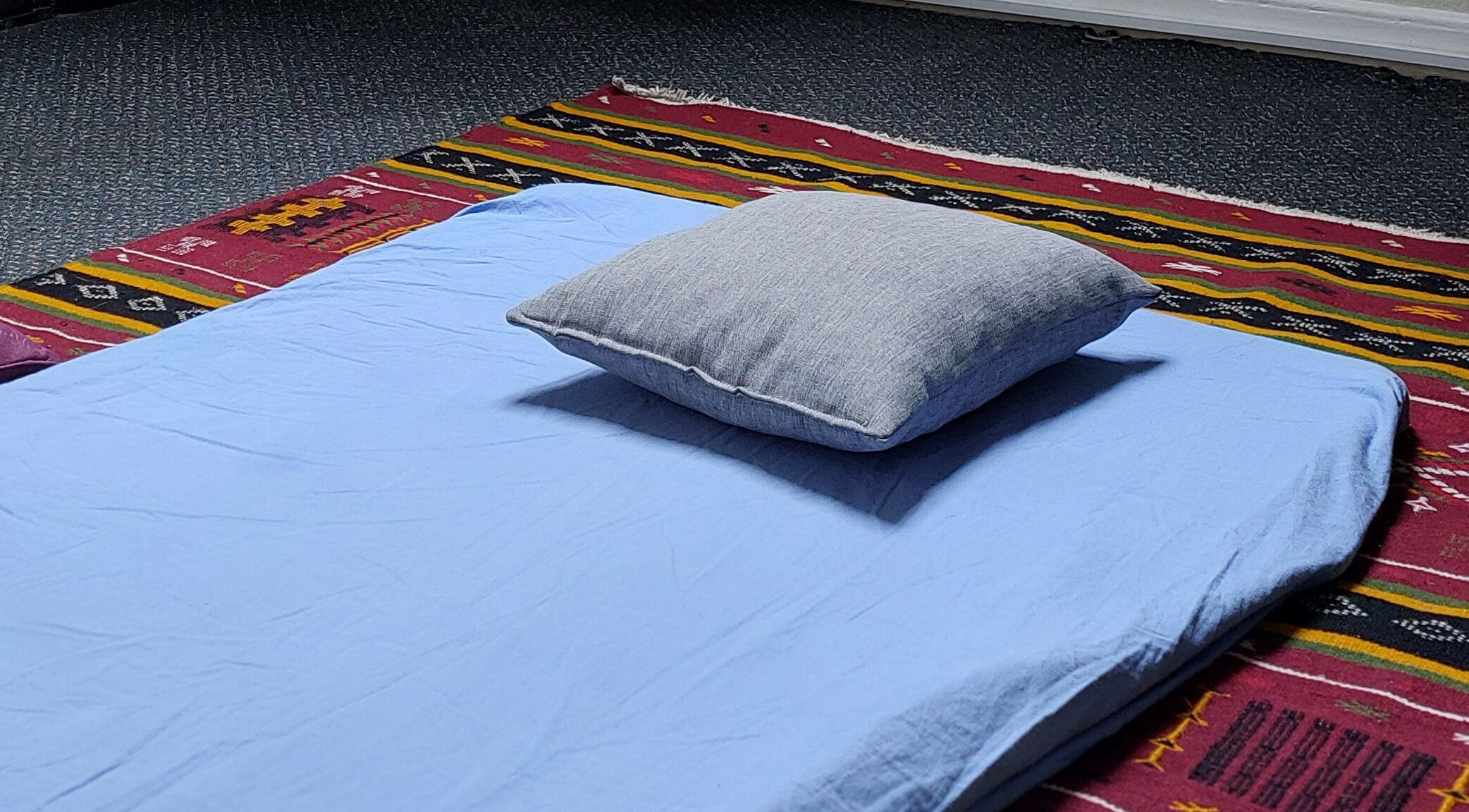Relaxation mat setup at City Zen Sanctuary, Edinburgh, Scotland, GB, on a vibrant patterned rug.