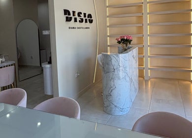 Recepción moderna en Disio Nails, Chihuahua, Chihuahua, MX, con mostrador de mármol y detalles de iluminación elegante.