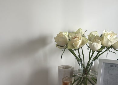 White roses in a vase and a price list at The Lux Studio, Villawood, New South Wales, AU.
