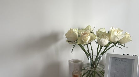 White roses in a vase and a price list at The Lux Studio, Villawood, New South Wales, AU.