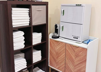 Tidy storage area with fresh towels and coffee maker at OMI MASSAGE in Lawrenceville, Georgia, US.