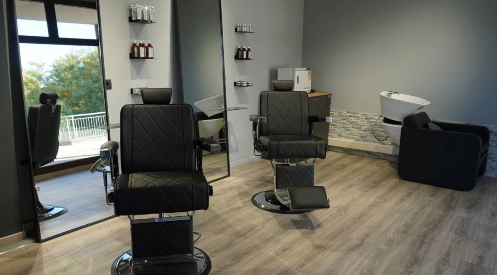 Interno moderno di Blend Barber Studio a Morazzone, Lombardia, IT con poltrone nere eleganti.