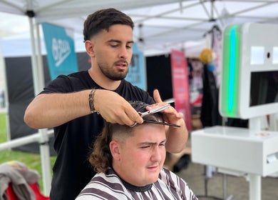 Coiffeur stylisant un client à Chez Dam’s, Garidech, Occitanie, FR sous tente moderne.