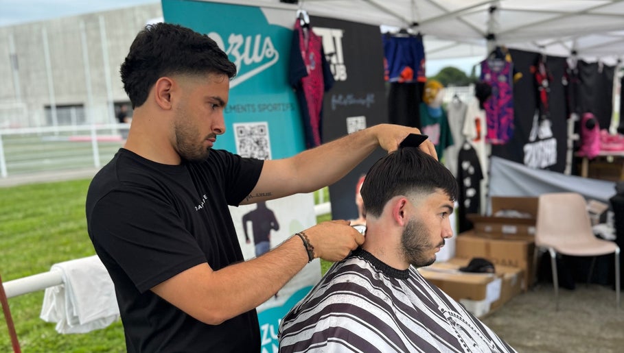 Coiffeur créant une coupe moderne chez Chez Dam’s, Pechbonnieu, Occitanie, FR sous un chapiteau.