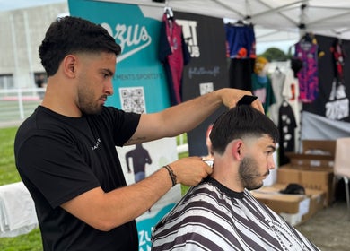 Coiffeur créant une coupe moderne chez Chez Dam’s, Pechbonnieu, Occitanie, FR sous un chapiteau.