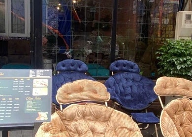 Không gian ghế thư giãn ngoài trời tại Ola spa, Đà Nẵng, Đà Nẵng, VN với bảng menu và cây xanh.