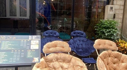 Không gian ghế thư giãn ngoài trời tại Ola spa, Đà Nẵng, Đà Nẵng, VN với bảng menu và cây xanh.