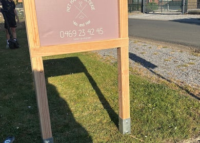 Bord van HethaarBoetiekje op grasveld bij Maaseik, Vlaanderen, BE met telefoonnummer vermeld.
