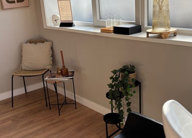 Stijlvolle wachtkamer in HethaarBoetiekje, Maaseik, Vlaanderen, BE met comfortabele stoel en groene plant.