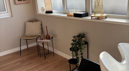 Stijlvolle wachtkamer in HethaarBoetiekje, Maaseik, Vlaanderen, BE met comfortabele stoel en groene plant.