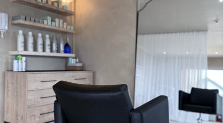 Interior of Tam's Chair in Cape Town, Western Cape, ZA, featuring a stylish black salon chair and shelves with beauty products.